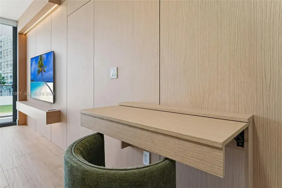 Custom wood-finish millwork wall paneling, built-in floating media console with integrated LED lighting, and retractable wall-mounted desk