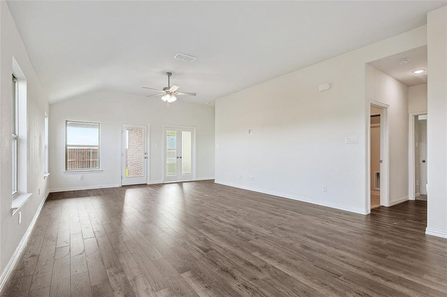 Empty room with vaulted ceiling, dark wood-type flooring, and ceiling fan