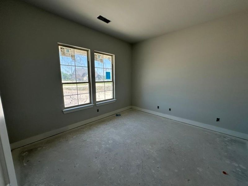 Room featuring dual windows with multi-pane grilles, neutral wall paint, and white baseboards