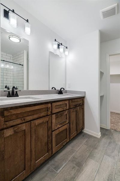 Full bathroom with double vanity, light wood-style floors, and a shower stall Full bathroom with double vanity, light wood-style floors, and a shower stall