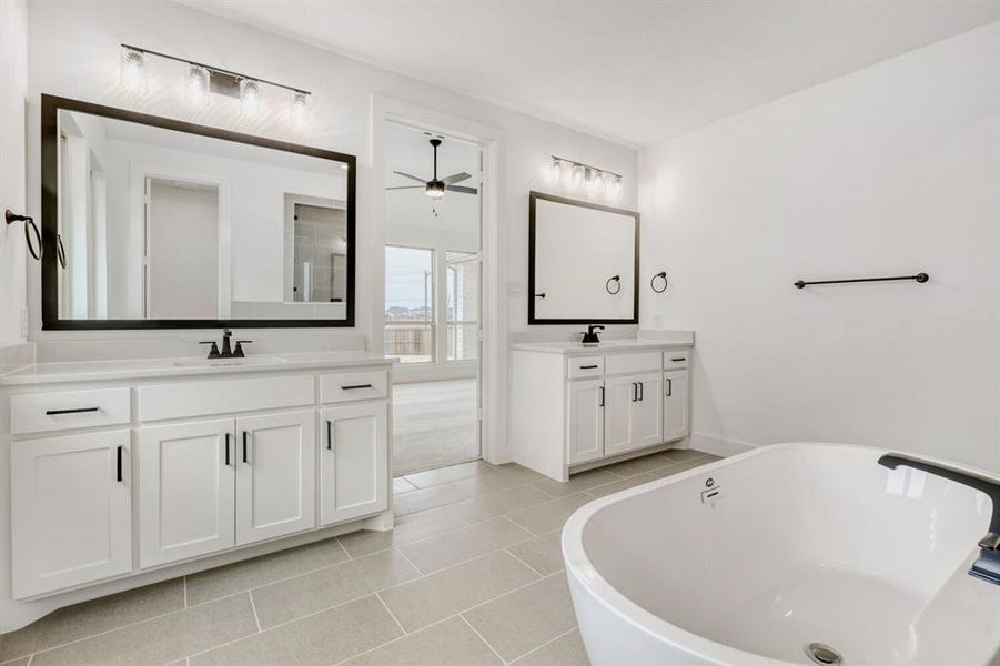 Bathroom with a freestanding tub, two vanities, light tile patterned floors, and ceiling fan
