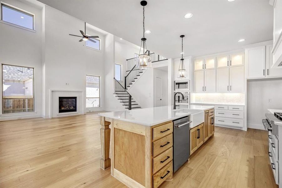 Kitchen featuring a glass covered fireplace, open floor plan, decorative light fixtures, decorative backsplash, and glass fronted cabinets