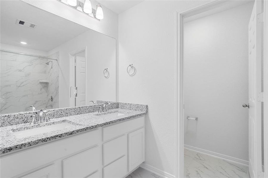 This primary bathroom is definitely move-in ready! Featuring an oversized tub and shower combination with tile surround, stained cabinets with granite countertops, high ceilings, neutral paint, sleek and modern finishes.