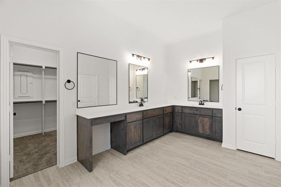 Full bath featuring double vanity, light wood finished floors, and a walk in closet Full bath featuring double vanity, light wood finished floors, and a walk in closet