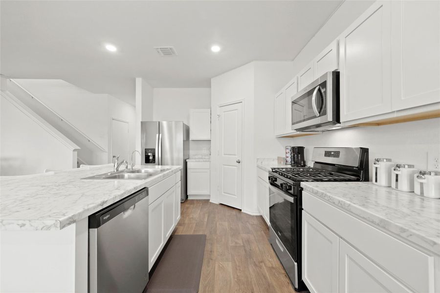 The ultimate command center! With its sleek stainless steel appliances, crisp white cabinetry, and massive prep island, this kitchen is as functional as it is beautiful.