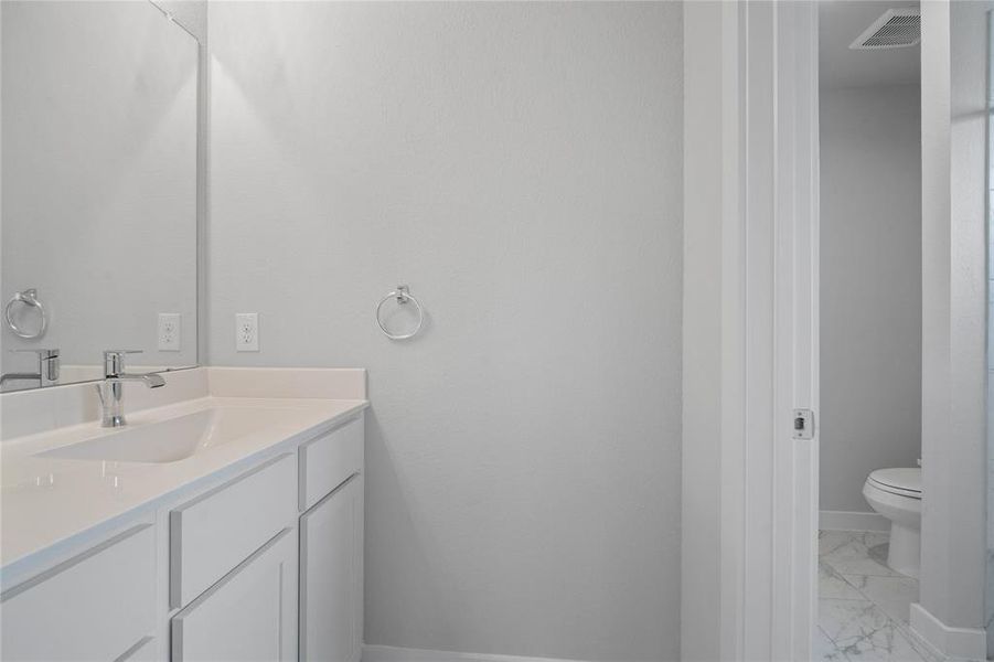 Secondary bath features a private vanity area and then opens to a shared tub/shower combo and toilet. Features include tile flooring, bath/shower combo with tile surround, wood stained cabinets, beautiful light countertops, mirror, dark, sleek fixtures and modern finishes!