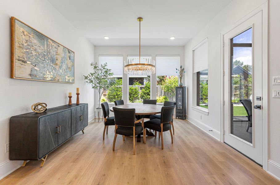 The dining room is enhanced by large windows overlooking the backyard and a designer light fixture.