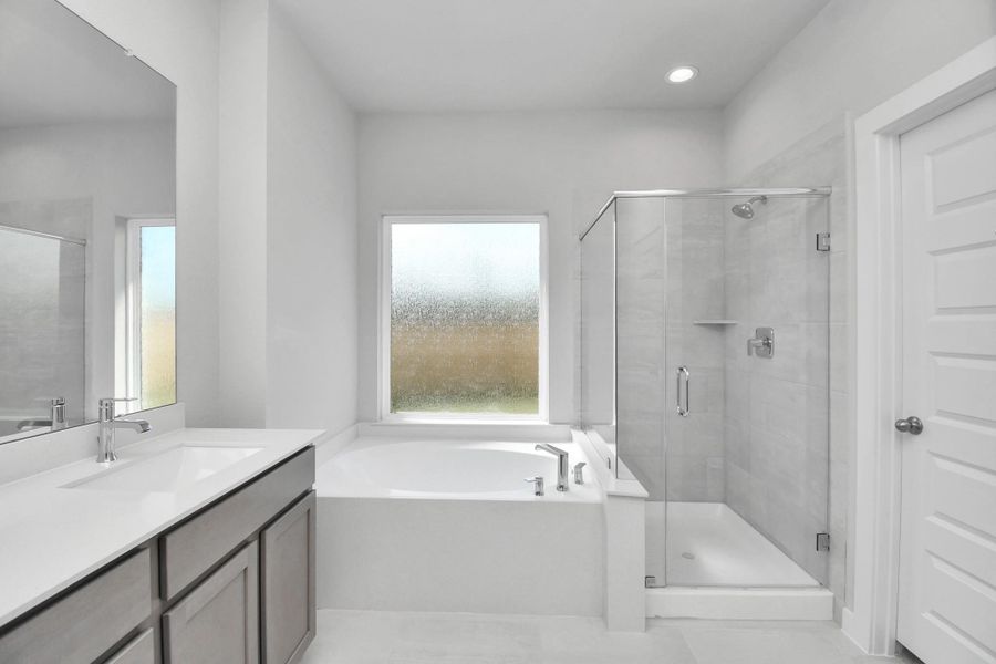 Indulge in a spa-like retreat within the confines of this primary bathroom. Delight in a spacious walk-in shower enveloped in stylish tile surround and unwind in a separate garden tub adorned with custom detailing. Sample photo of completed home with similar floor plan. Actual colors and selections may vary. Indulge in a spa-like retreat within the confines of this primary bathroom. Delight in a spacious walk-in shower enveloped in stylish tile surround and unwind in a separate garden tub adorned with custom detailing. Sample photo of completed home with similar floor plan. Actual colors and selections may vary.