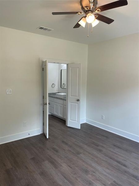 Unfurnished bedroom with ceiling fan and dark wood-type flooring