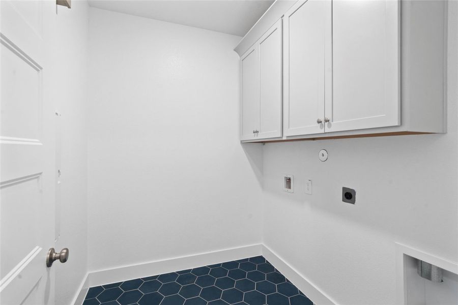 This bright and functional laundry room is conveniently located and ready for your appliances. It features clean white walls and trim, grey cabinetry to fit your laundry supplies, and the gorgeous decorative tile flooring for durability.