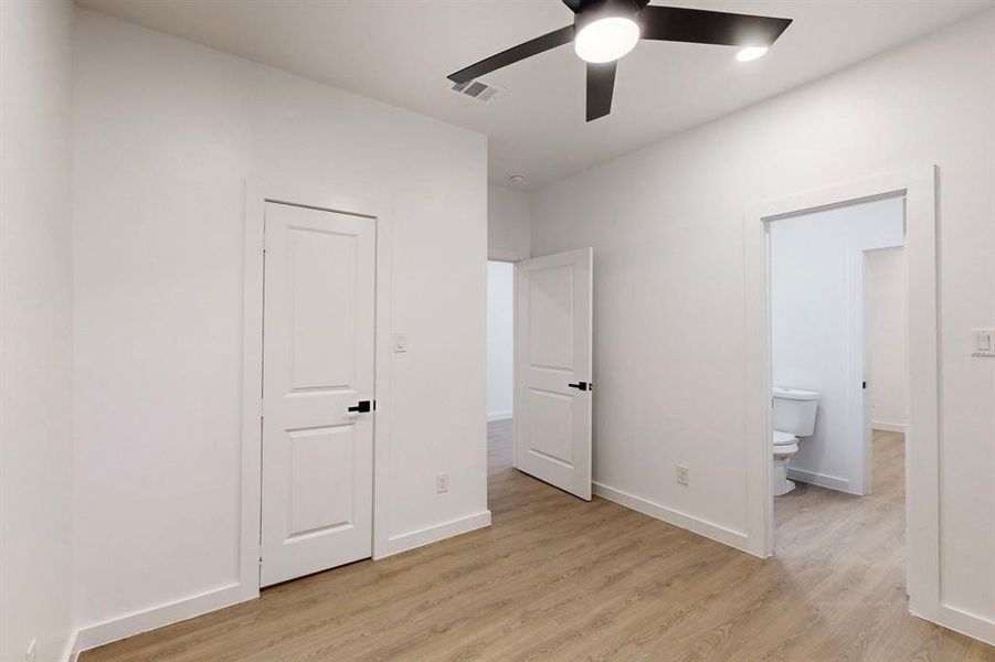 Unfurnished bedroom featuring ensuite bathroom, light hardwood / wood-style flooring, and ceiling fan