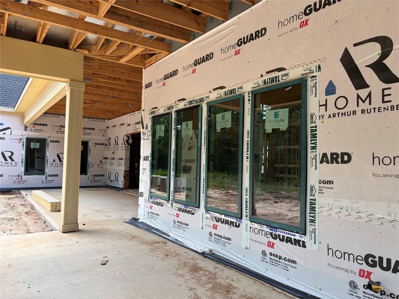 Under-construction patio area features large sliding glass doors and a partially covered roof, offering a glimpse of the future outdoor living space. Under-construction patio area features large sliding glass doors and a partially covered roof, offering a glimpse of the future outdoor living space.