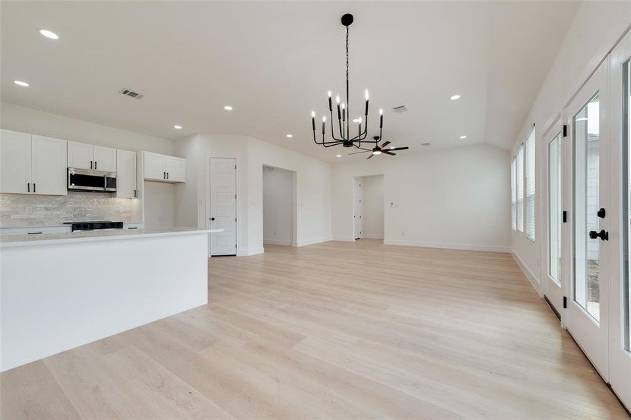 Kitchen with white cabinetry, an inviting chandelier, decorative backsplash, decorative light fixtures, and light wood-type flooring