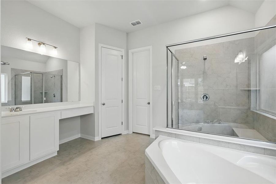 Bathroom featuring a garden tub, vanity, and a stall shower Bathroom featuring a garden tub, vanity, and a stall shower