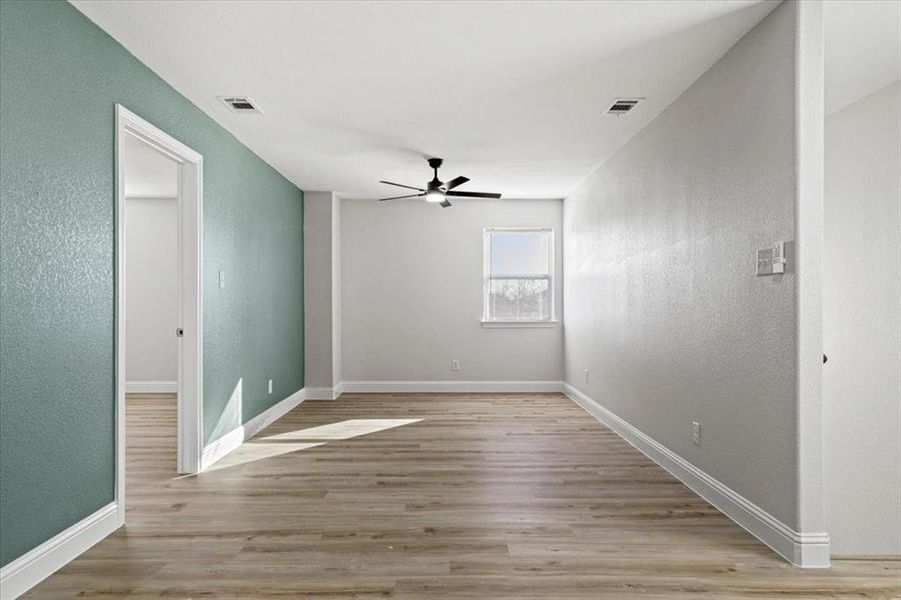 Empty room with ceiling fan and light wood-type flooring