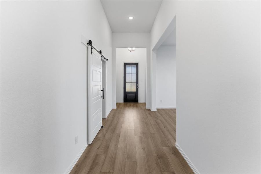 Doorway to outside featuring a barn door, wood finished floors, and recessed lighting