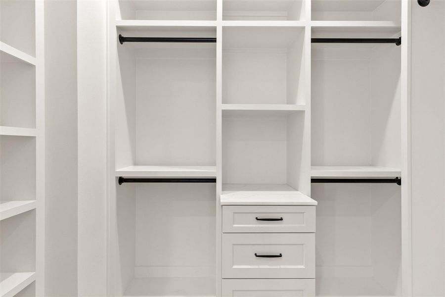 Custom built-in shelving and drawers keep every wardrobe organized, giving everything its own place.