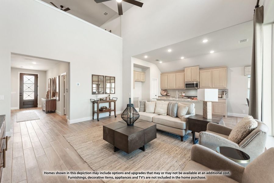 Open-concept living room with vaulted ceiling, wood-look floors, and kitchen visible in background