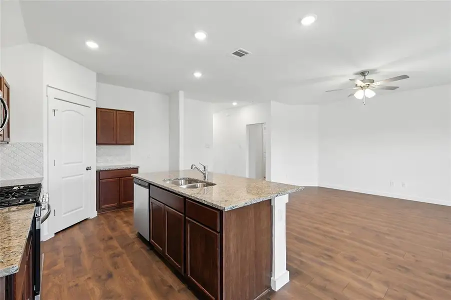 Kitchen with appliances with stainless steel finishes, dark wood-style flooring, decorative backsplash, ceiling fan, and recessed lighting Kitchen with appliances with stainless steel finishes, dark wood-style flooring, decorative backsplash, ceiling fan, and recessed lighting