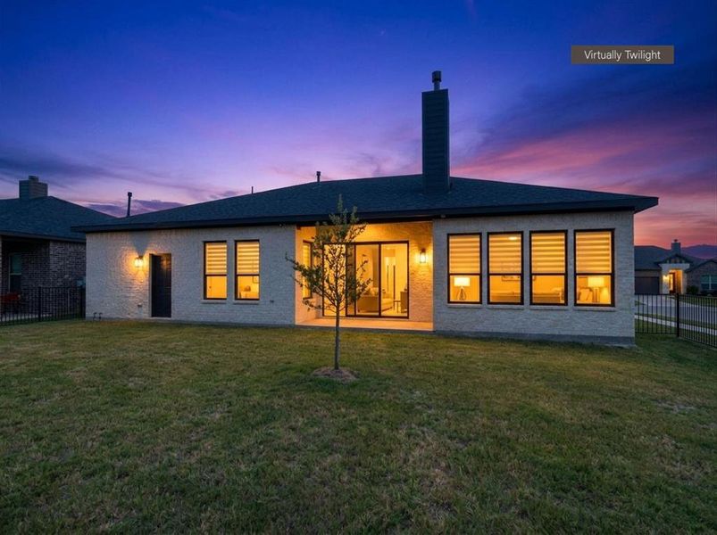 Expansive rear exterior featuring a grass lawn, a covered patio, and multiple large windows with horizontal blinds