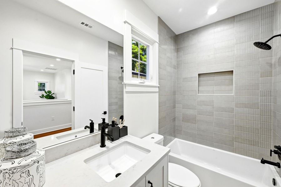 A well-lit bath features a bright window and contemporary tiled shower with an integrated niche. A well-lit bath features a bright window and contemporary tiled shower with an integrated niche.
