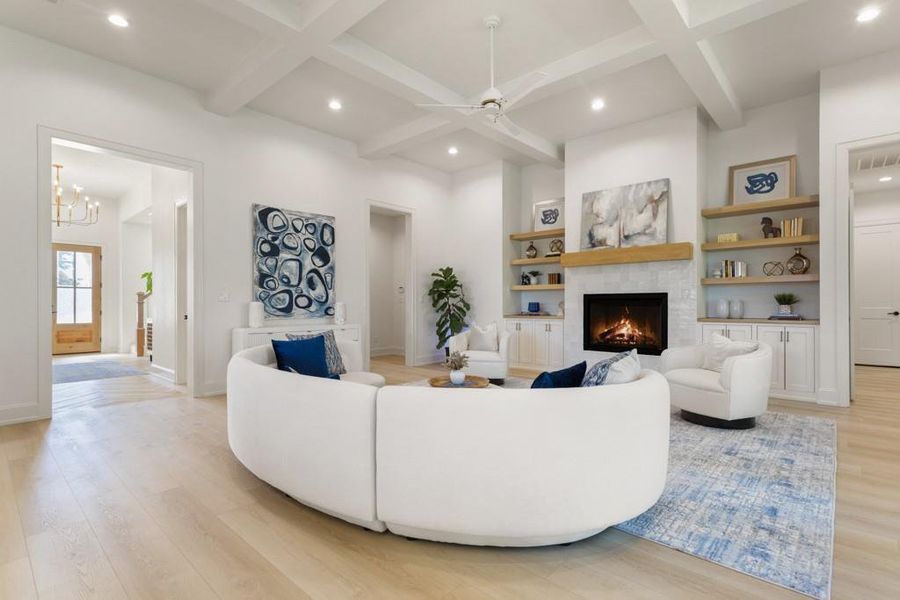 Living area with recessed lighting, light wood-style floors, a warm lit fireplace, beamed ceiling, and a ceiling fan