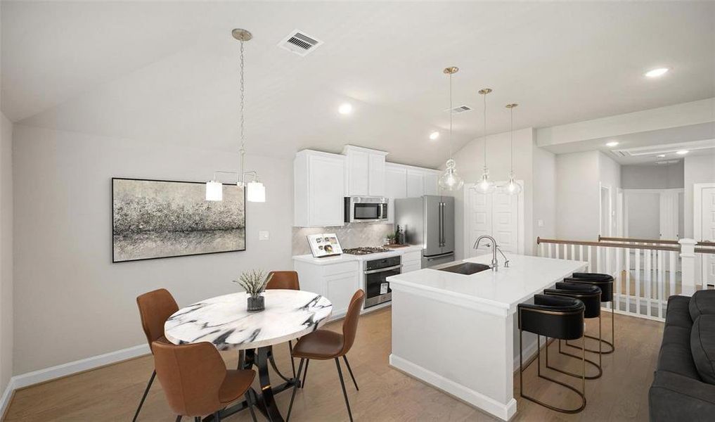 The kitchen features pendant and recessed lighting, stainless steel appliances, and a beautiful modern white aesthetic.