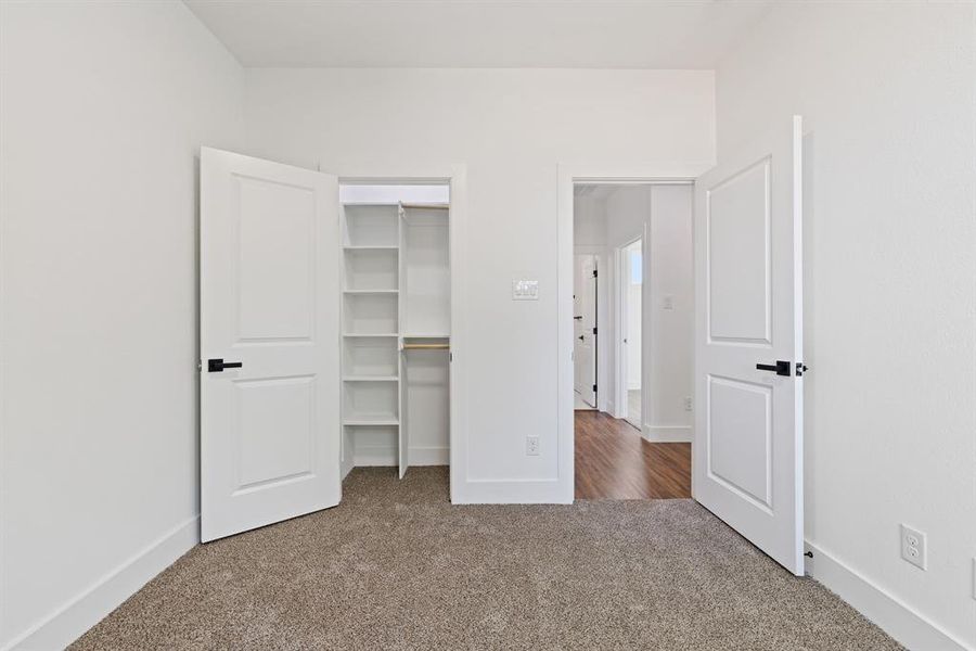 Unfurnished bedroom featuring dark carpet and a spacious closet
