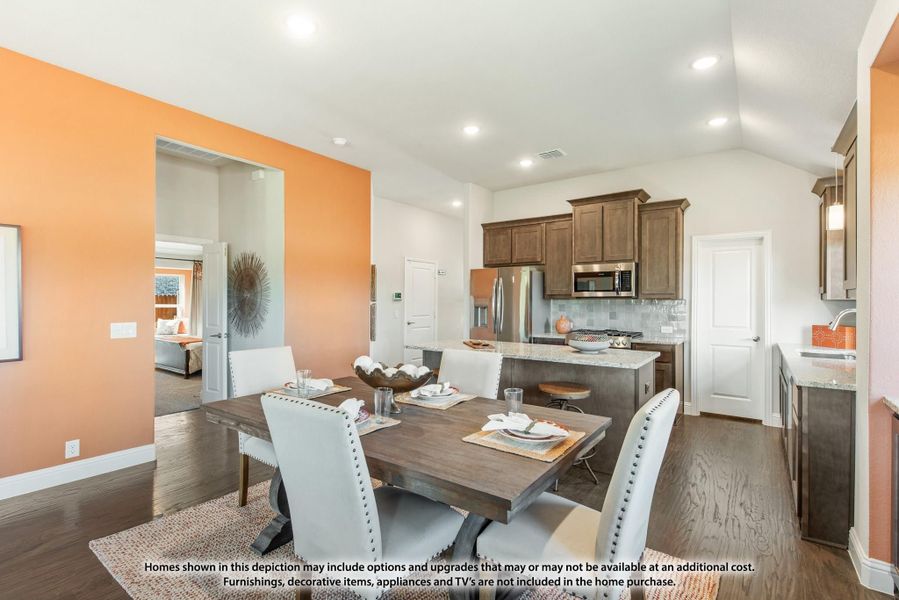 Open dining area with wood table and white chairs, connected to kitchen with dark cabinets and stainless appliances Open dining area with wood table and white chairs, connected to kitchen with dark cabinets and stainless appliances