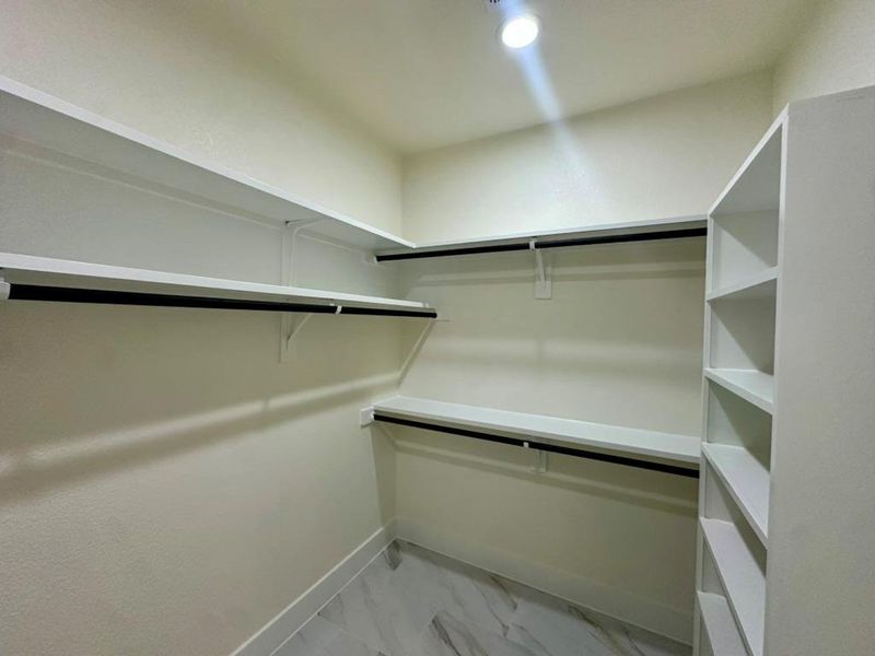 Walk in closet with light marble finish floors