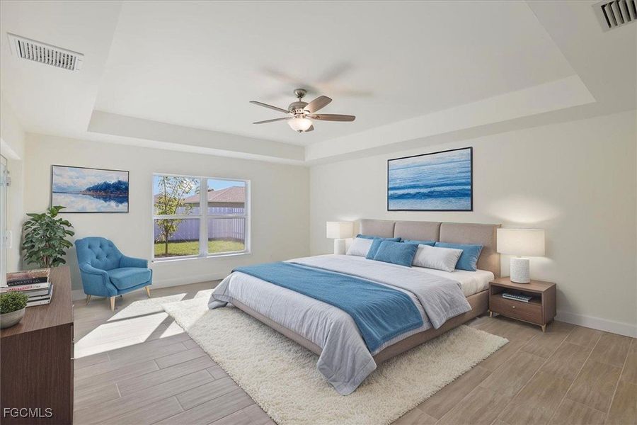 Bedroom with a raised ceiling, wood finish floors, and ceiling fan