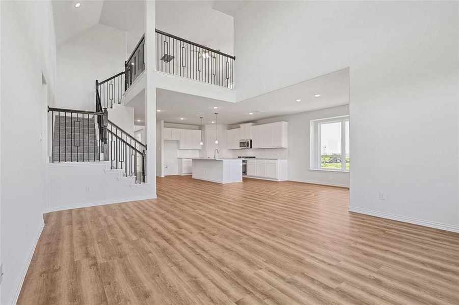 Unfurnished living room with light wood-type flooring, sink, and high vaulted ceiling