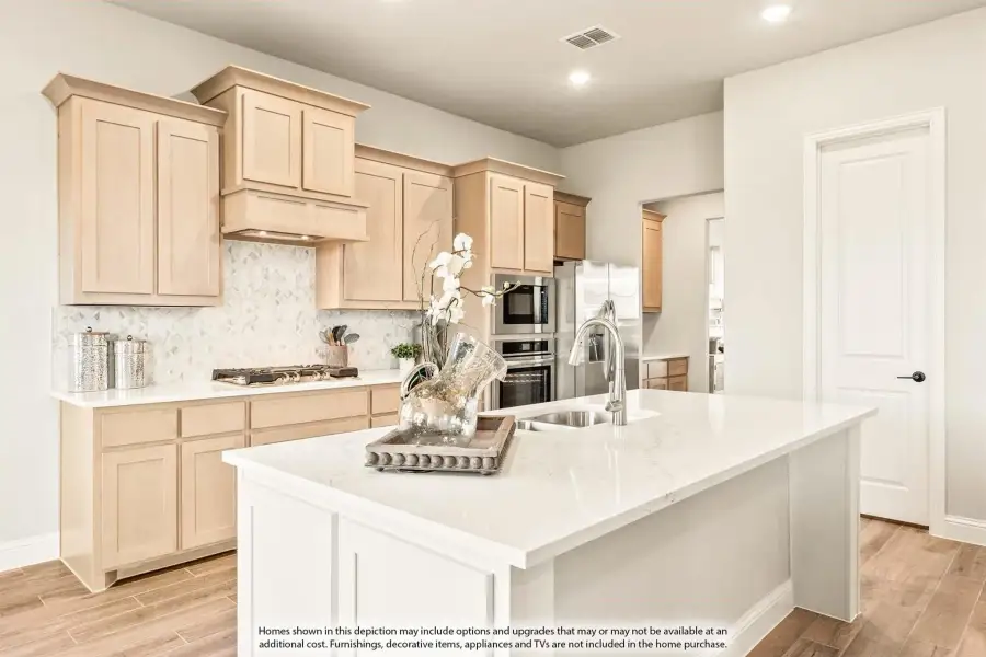 Kitchen with light wood cabinets, white quartz island, tile backsplash, and stainless steel appliances on wood-look floors.