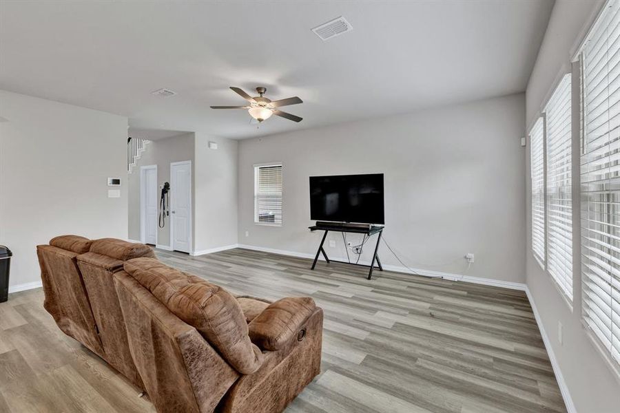 Living area featuring light gray walls, gray wood-look flooring, and a ceiling fan with integrated lighting