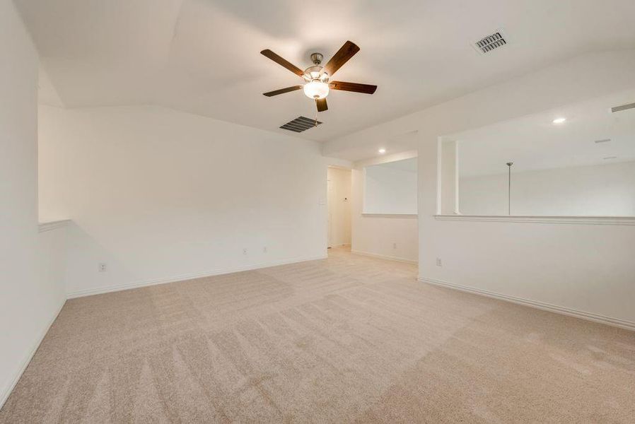 Unfurnished room with ceiling fan, light colored carpet, and vaulted ceiling