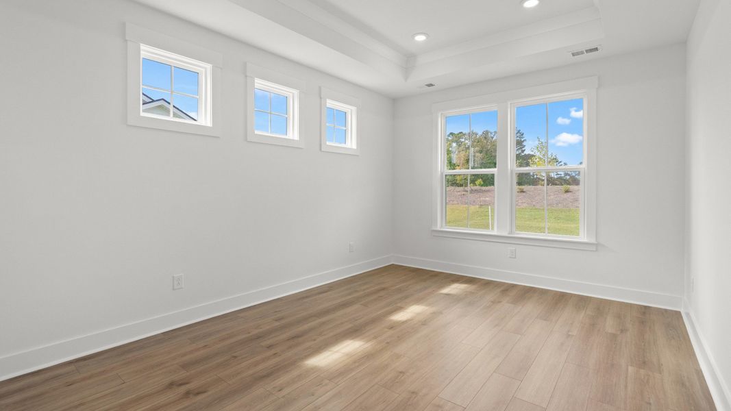 Spacious primary suite with tray ceiling and sunlit windows for a relaxing retreat. Spacious primary suite with tray ceiling and sunlit windows for a relaxing retreat.