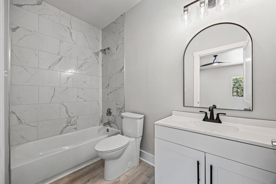 Full bathroom with bathtub / shower combination, vanity, and light wood-type flooring Full bathroom with bathtub / shower combination, vanity, and light wood-type flooring