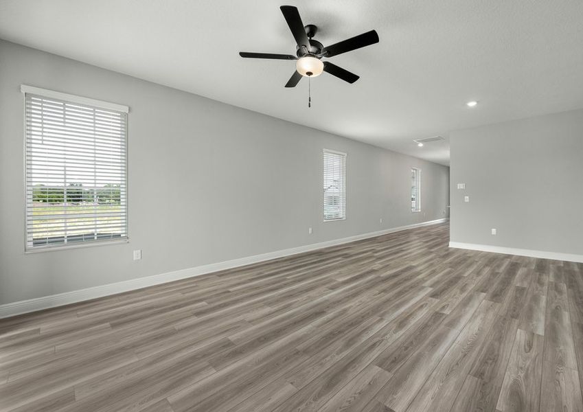 Family room with a ceiling fan and three windows with faux blinds
