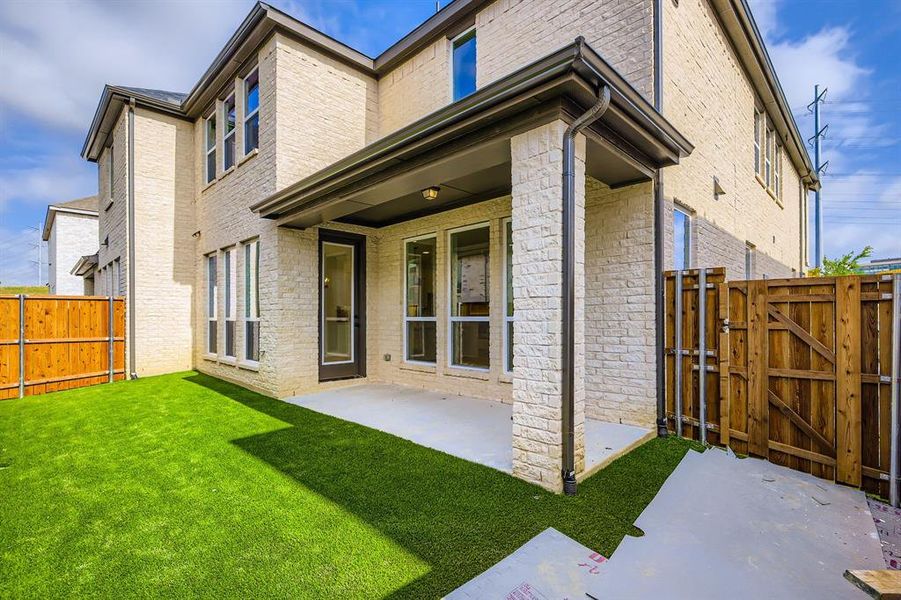 Rear view of property featuring a gate, a patio area, a fenced backyard, and brick siding