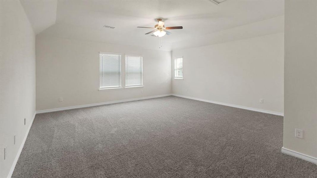 Spacious room featuring gray carpet, light-toned walls, and a ceiling fan with integrated lighting