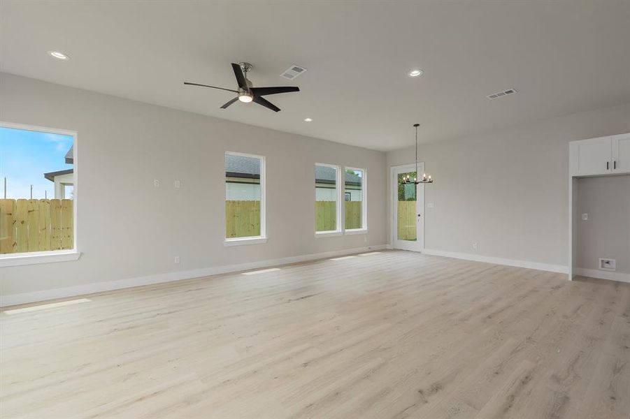 Unfurnished living room with a chandelier, light wood-style flooring, ceiling fan, recessed lighting, and baseboards