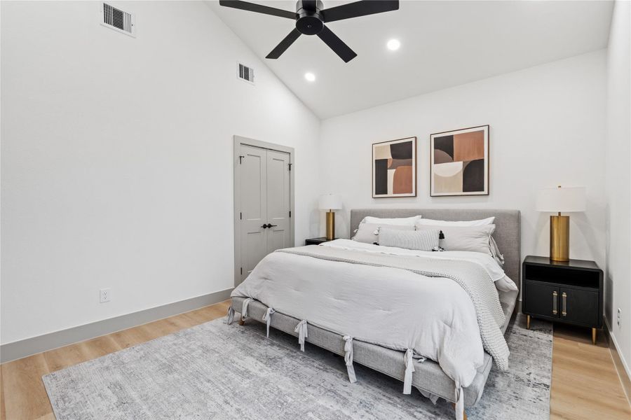 Wake up beneath soaring vaulted ceilings and unwind in the glow of natural light streaming through oversized windows. This serene primary bedroom blends modern scale with cozy texture, creating a calming space to start and end each day.