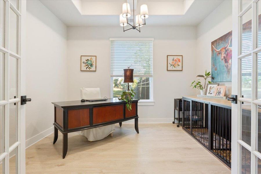 Office space featuring light wood-style flooring, a beamed ceiling, suspended lighting, and glass french doors