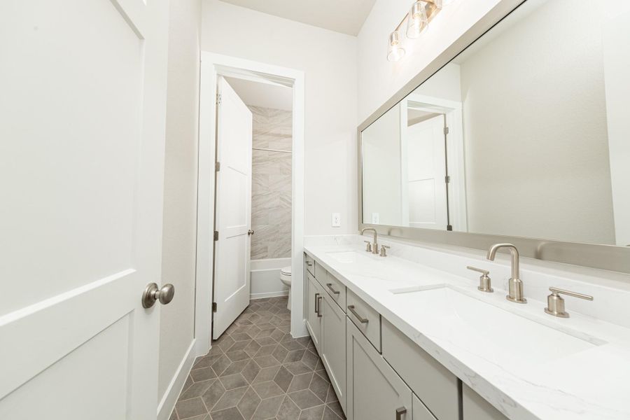 The secondary bathroom features a dual vanity, framed mirror, tub/shower combination with gorgeous tile surround, and modern brushed nickel finishes. The secondary bathroom features a dual vanity, framed mirror, tub/shower combination with gorgeous tile surround, and modern brushed nickel finishes.