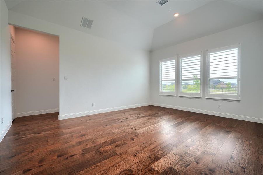 Spare room featuring dark wood finished floors, vaulted ceiling, and recessed lighting