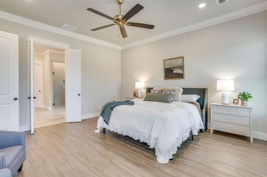 Spacious bedroom featuring wood-finish flooring, crown molding, a ceiling fan with integrated lighting, and recessed ceiling lights