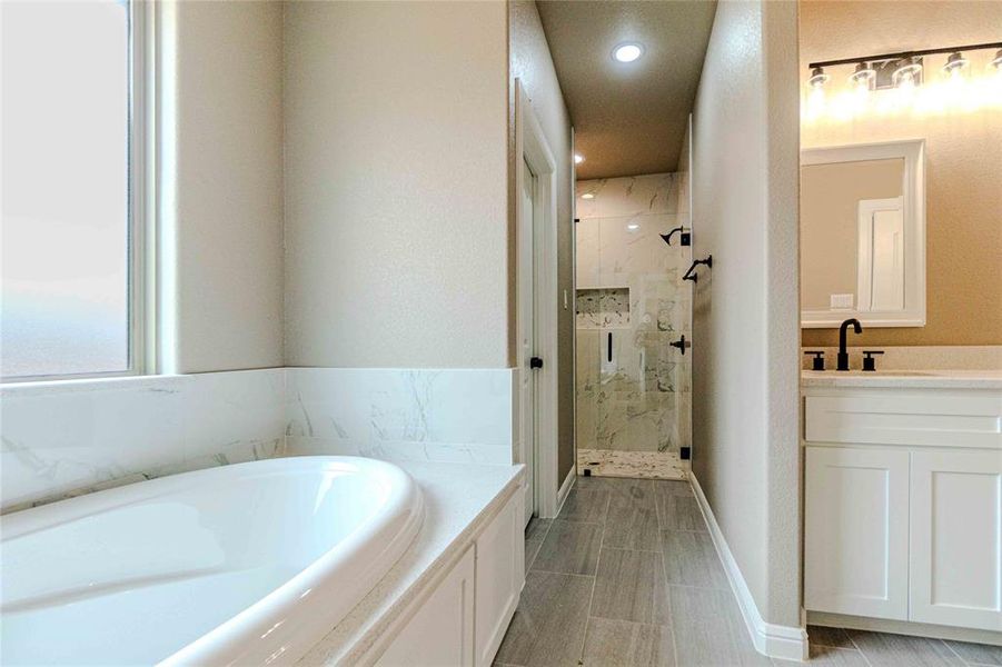 Bathroom featuring vanity and shower with separate bathtub