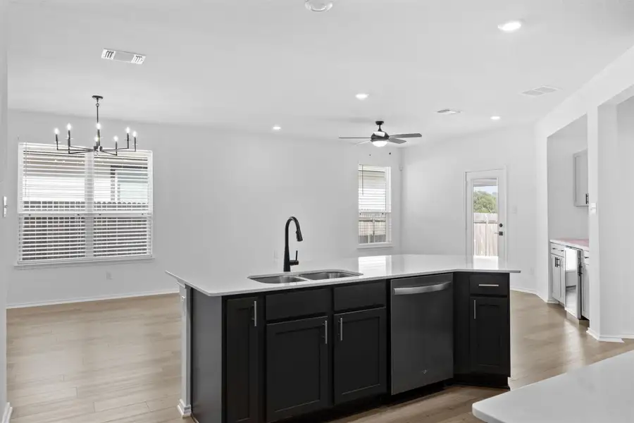 Kitchen featuring dark cabinetry, recessed lighting, light wood-style flooring, stainless steel dishwasher, and an island with sink
