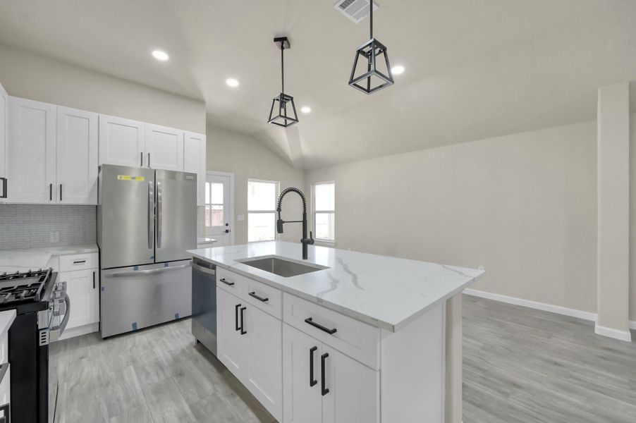 The oversized prep island features a deep under-mount sink, high-neck pull-down faucet, and ample space for casual bar-stool seating.