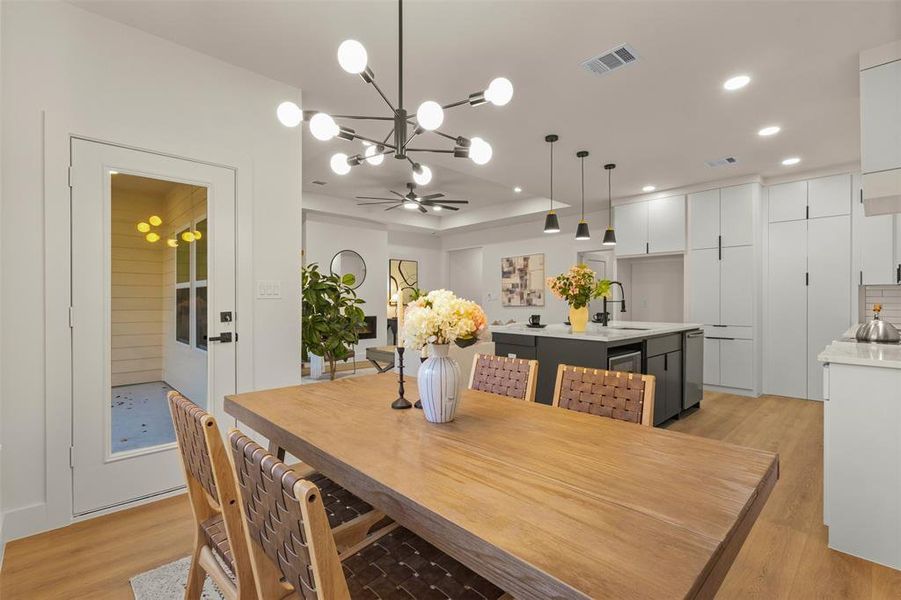 Dining room featuring light wood finished floors, a chandelier, a tray ceiling, and recessed lighting